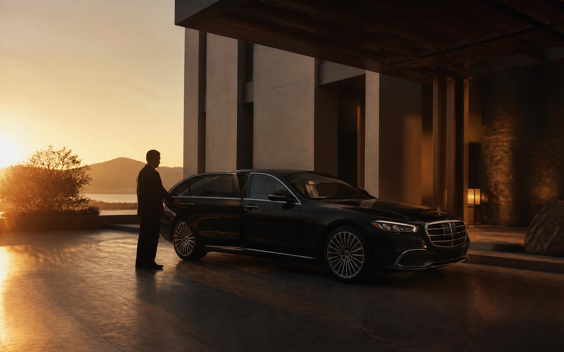 Chauffeur opening the door of a black Mercedes S-Class at a luxury hotel at golden hour